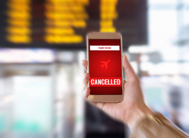 Flight cancelled. Smartphone application announces bad news to tourist. Strike or problem with plane. Woman holding mobile phone in airport terminal. Timetable and schedule in the blurred background. Transportation and mobile services cancelled stock pictures, royalty-free photos & images