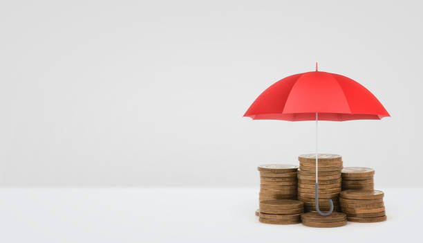istock A red open umbrella vertically placed over several stacks of golden coins on white background 679924092