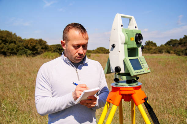 istock Man using of total station. Guy surveyor at work. Survey Instrument geodetic device, total station set and surveyor worker making measurement in the field. Total station outdoor at construction site. 679924104