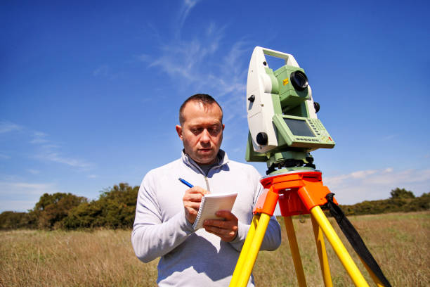 istock Man using of total station. Guy surveyor at work. Survey Instrument geodetic device, total station set and surveyor worker making measurement in the field. Total station outdoor at construction site. 679924134