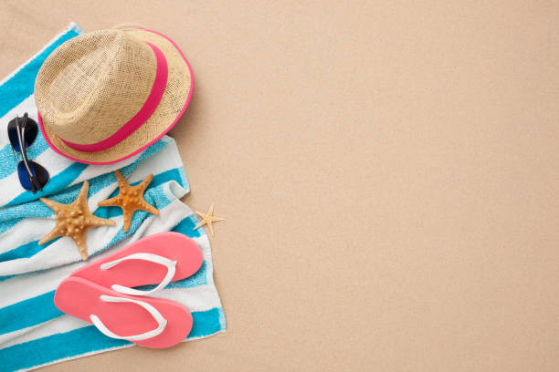Beach accessories for perfect vacation! Beach accessories: pink flipflop, straw hat, towel and sunglasses isolated on sand. starfish sunglasses stock pictures, royalty-free photos & images