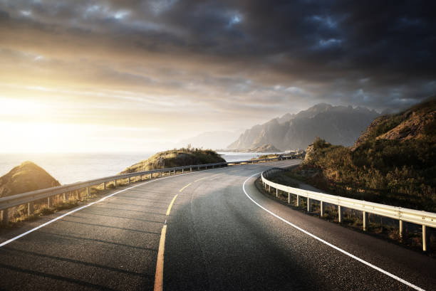 oad junto al mar en el tiempo del amanecer, isla de lofoten, noruega - road street nature mountain peak fotografías e imágenes de stock