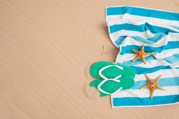 istock Beach towel and flip-flops on ocean beach sand. 679941032