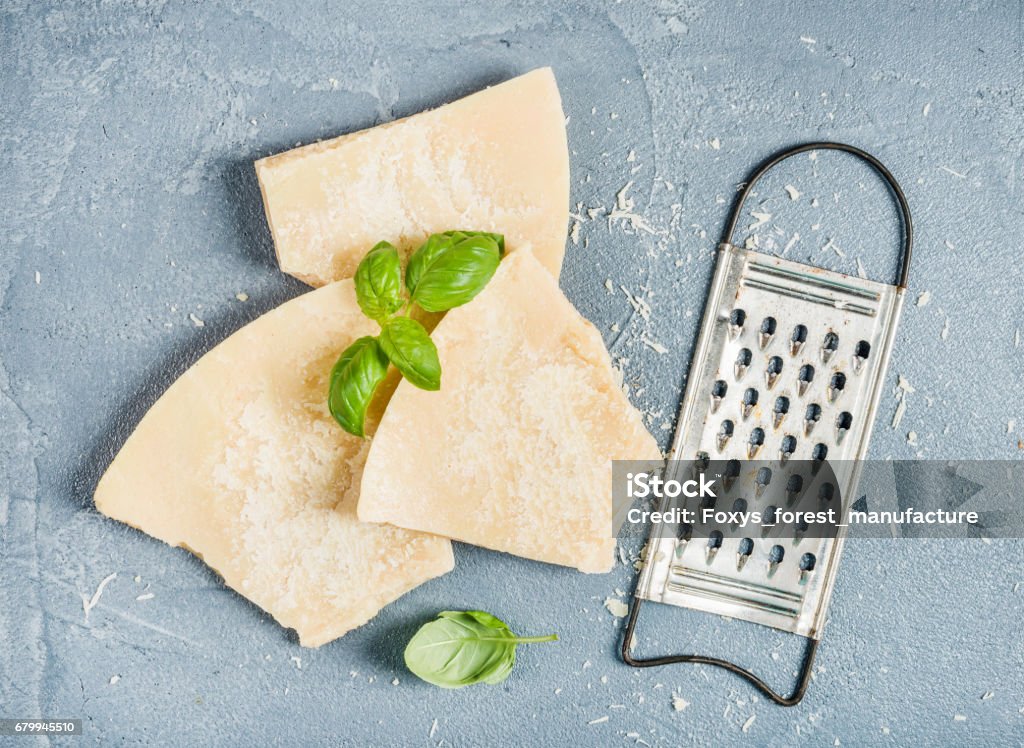 Kürzungen der Parmesan-Käse mit Metall Reibe und frischem Basilikum über konkrete strukturierten Hintergrund - Lizenzfrei Parmesan Stock-Foto