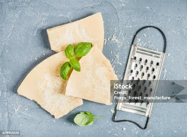 Kürzungen Der Parmesankäse Mit Metall Reibe Und Frischem Basilikum Über Konkrete Strukturierten Hintergrund Stockfoto und mehr Bilder von Parmesan