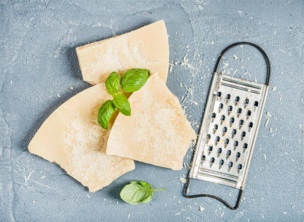 cuts of parmesan cheese with metal grater and fresh basil over concrete textured background - recipe ingredient grater cheese grater imagens e fotografias de stock