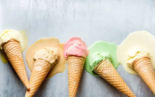 Colorful ice cream cones of different flavors. Melting scoops. Top view, copy space, steel metal background