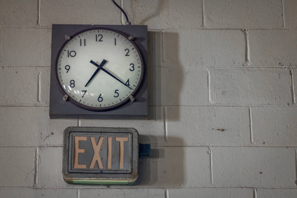 Clock on a block wall Clock on a block wall with exit sign below abandoned place photos stock pictures, royalty-free photos & images