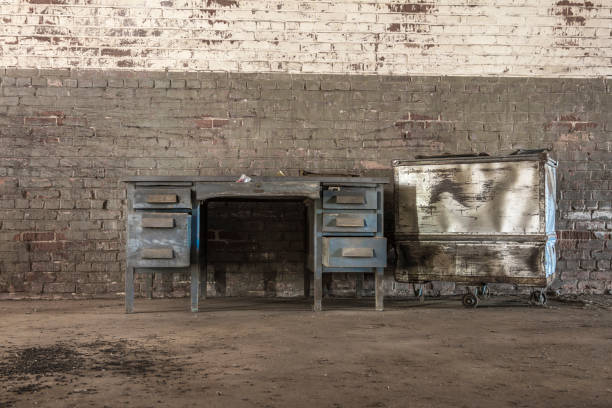 Empty desk and a metal case against a brick wall