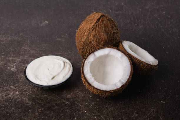 Coconut, cream, coconut milk and oil on a dark marble background. Exotic large walnut. Personal care. Spa treatments