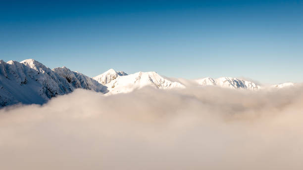 istock mountain tops in winter covered in snow with bright sun and blue sky 679975554