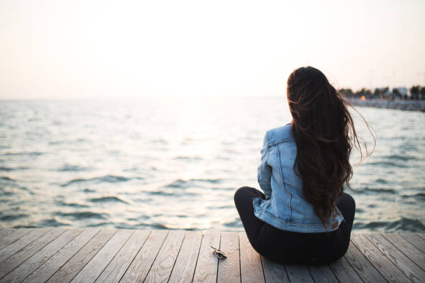 istock Young woman sitting looking sunset 679984784
