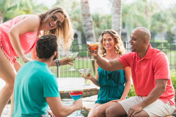 istock Two couples enjoying drinks by resort swimming pool 679991204