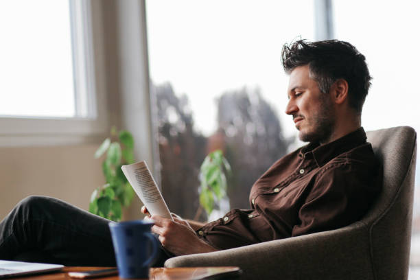 istock Young man reading a book at home 679993438