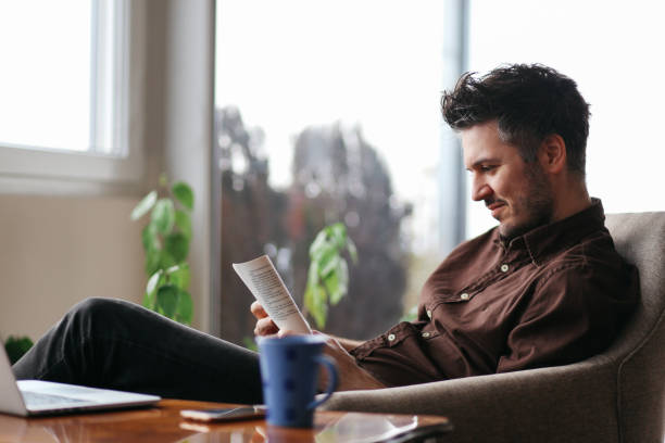 istock Young man reading a book at home 679994568
