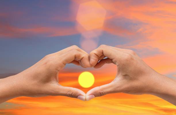 istock hand forming  a heart shape with  sunset  light and copy space for add text 680022456