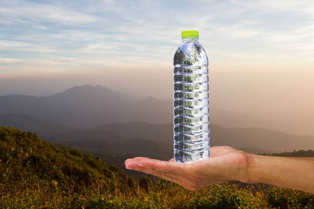 istock Hand holding drinking water bottle on blurred green bokeh background 680022494