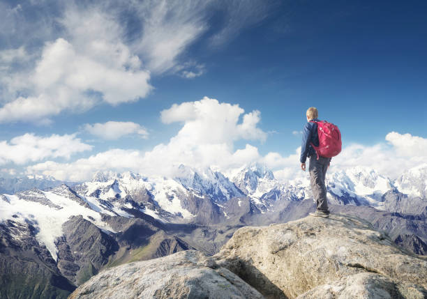 Young hiker man standing on a mountain arms outstretched. Freedom concept. Spectacular snowcapped mountain scenery.