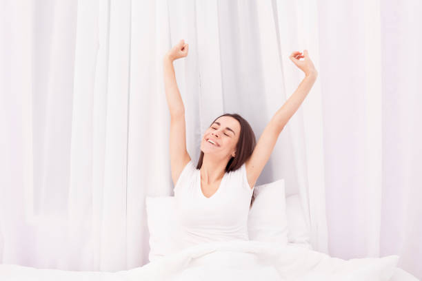 istock Girl waking up stretching arms on the bed 680054032