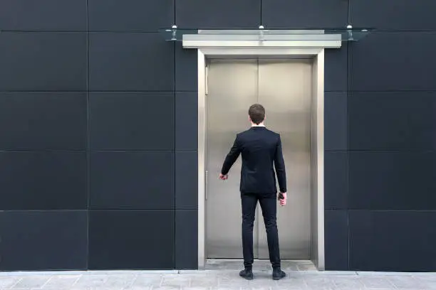 Rear view of an unrecognizable Caucasian male businessman using elevator.