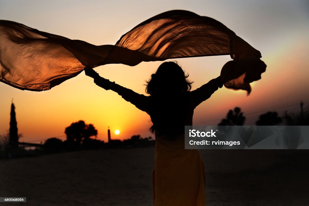 Women silhouette in the nature Beautiful young woman holding yellow scarf on the wind. Freedom Stock Photo