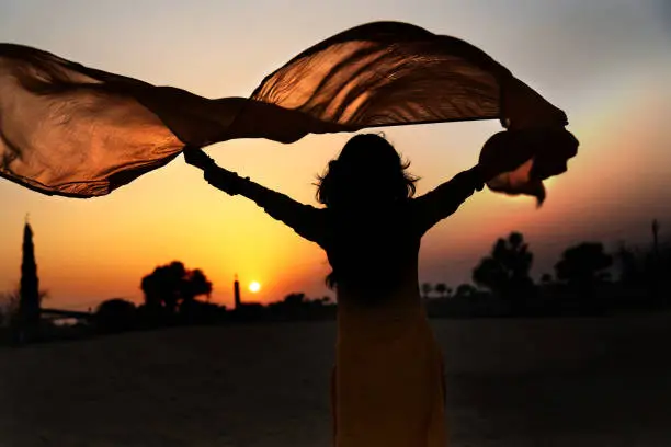 Beautiful young woman holding yellow scarf on the wind.