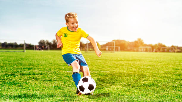 istock Happy boy runs on soccer field and kicks ball 680068642