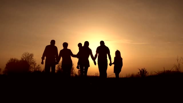 Three generation family walk in meadow at sunset