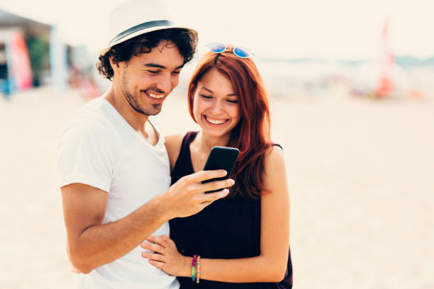 Young couple texting at the beach