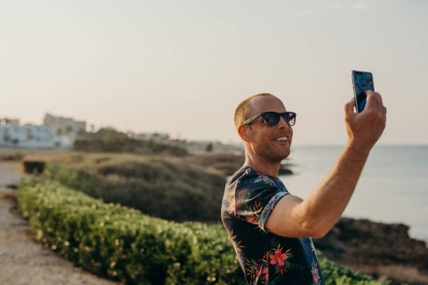 istock Man on vacation taking photo or selfie with smart phone 680071648