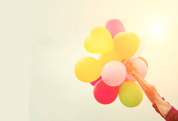 istock Young woman hands holding balloons against  sky 680079806