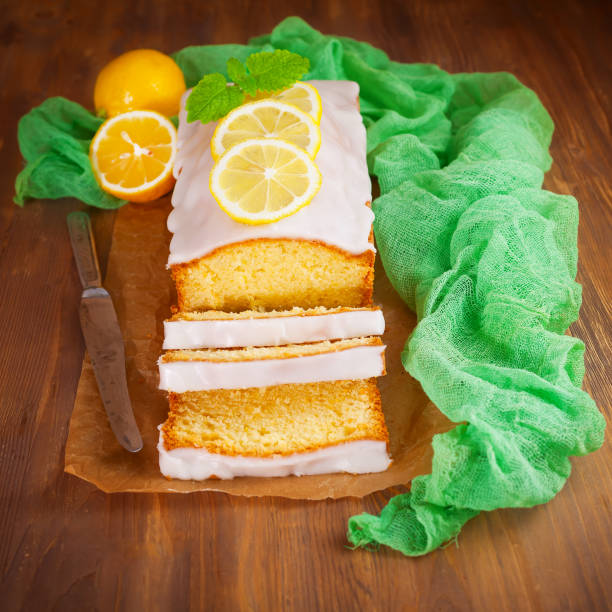 Homemade lemon pound cake with sweet lemon icing on rustic wooden table, sliced.