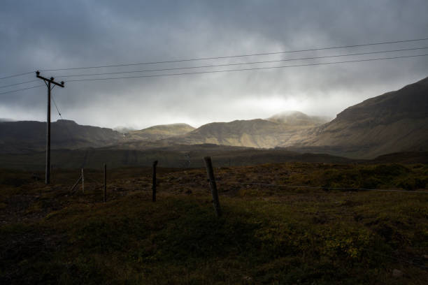 istock Power pole in Iceland. Light and shadow over the landscape. Beautiful mountain range in the backgrond. Tough nature. 680090096