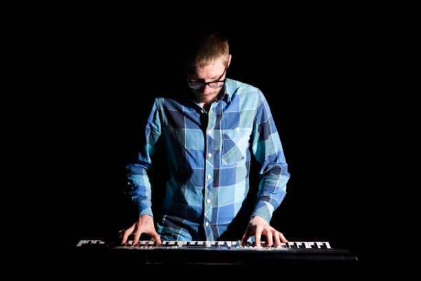 istock Keyboarder in plaid shirt playing on dark background 680100258
