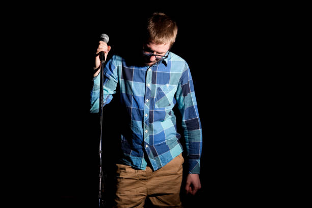 istock Male singer in plaid shirt singing with microphone over dark background 680100876