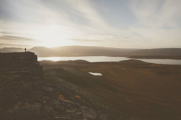 istock Hiker on a rocky cliff during the sunset. Great atmosphere with light and a spectacular perspective. Tough nature in Iceland. 680104350