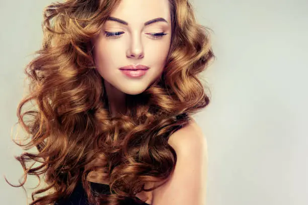 Photo of Young, brown haired woman  with voluminous, shiny and wavy hair.