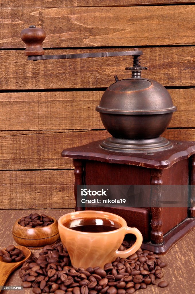 Old wooden coffee grinder and roasted coffee beans on a wooden table . Fresh hot coffee in Cup . Old wooden coffee grinder and roasted coffee beans on a wooden table. Fresh hot coffee in Cup . Black Color Stock Photo