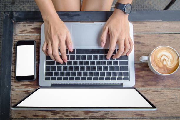 istock woman hands on laptop with mobile phone and coffee 680120998