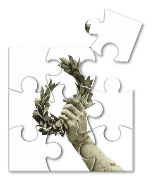 Photo of The slow construction of success and fame - Laurel wreath hand held by a bronze statue - concept image in jigsaw puzzle shape