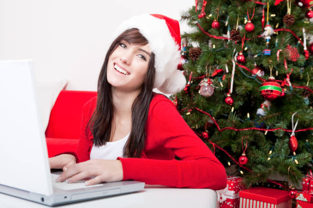istock Happy woman in santa hat using laptop 680124088