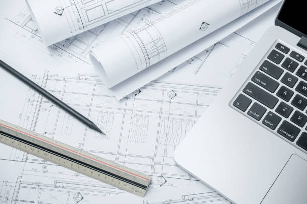black pencil and computer laptop on architectural drawing paper for construction stock photo