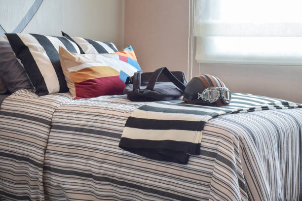 modern bedroom with helmet and bag on striped bedding