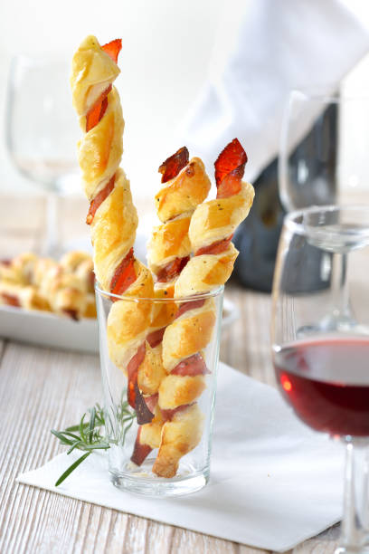 Puff pastry sticks Baked hearty puff pastry sticks with ham and herbs served with a glass of red wine twisted bacon stock pictures, royalty-free photos & images