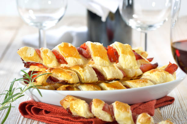 Puff pastry sticks Baked hearty puff pastry sticks with ham and herbs served with a glass of red wine twisted bacon stock pictures, royalty-free photos & images