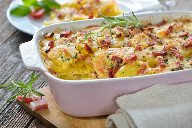 Potato gratin with bacon Hearty potato gratin with parmesan cheese, cream and delicious cured bacon from South Tyrol freshly served from the oven casserole stock pictures, royalty-free photos & images