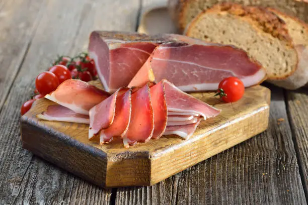 South Tyrolean bacon with fresh stone oven baked bread on a wooden table