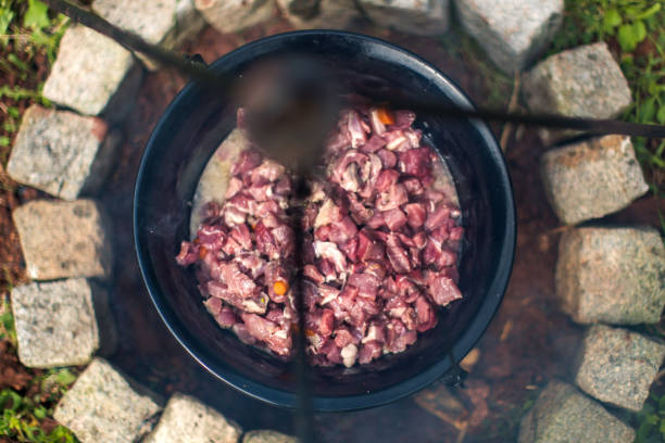 Cauldron, kettle with meet on fire.