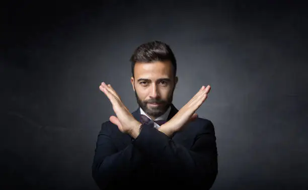 elegant man gesturing x with hands, dark background