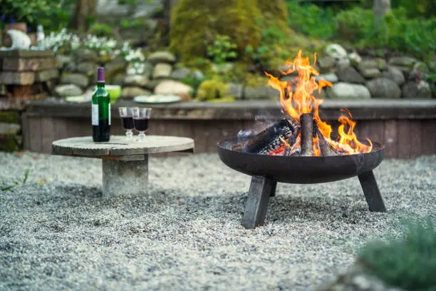 fire pit in a garden with two galss of red wine in the foreground